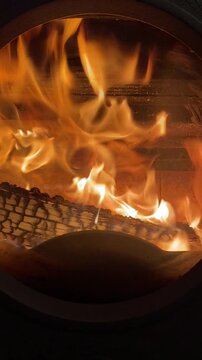 Close-up of a wood fire in a stove. You can see the flames dancing. Cozy and warm atmosphere