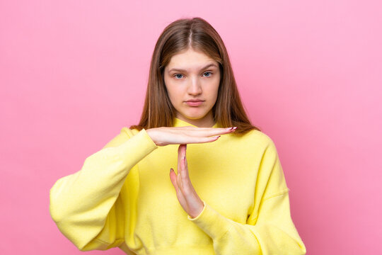 Teenager Russian girl isolated on pink background making time out gesture