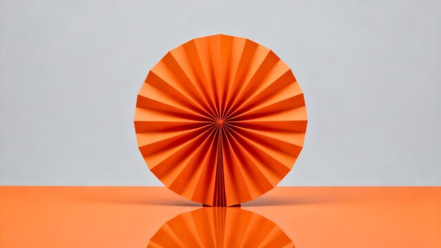 A single large abstract shape resembling a folded paper fan, made of glossy orange panels radiating from one point, standing upright against a plain light-grey background.