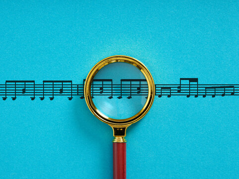 Magnifying glass analyzing musical score notes on blue