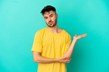 Fototapeta premium Young caucasian man isolated on blue background having doubts