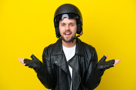 Young caucasian man with a motorcycle helmet isolated on yellow background with shocked facial expression