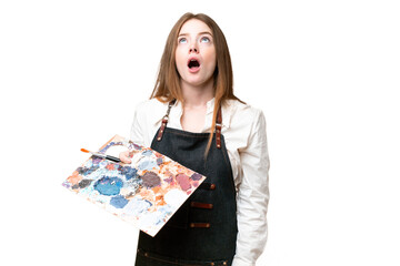 Young artist woman holding a palette over isolated chroma key background looking up and with surprised expression © luismolinero