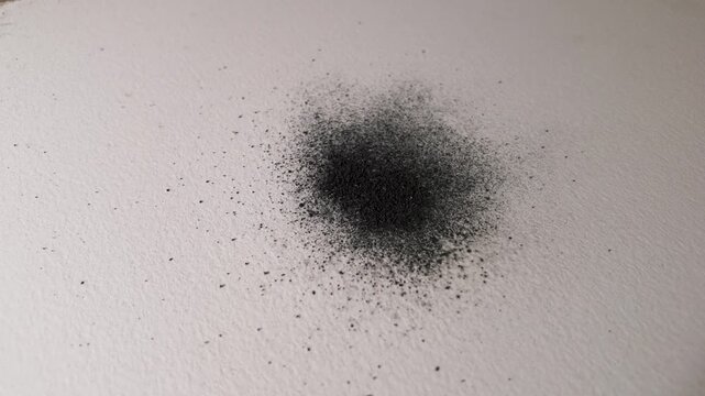 Watercolor graphite powder flowing through the grain of textured paper, subtle tonal changes developing in slow motion