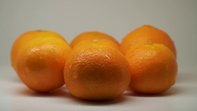 Fresh whole mandarin oranges rotating on white studio background.