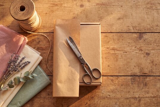 Kraft paper gift wrapping supplies laid out on a wooden table