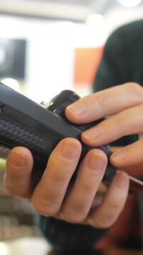 Customer making a contactless payment with a smartwatch, swiping the device on a credit card reader terminal for a cashless transaction and electronic purchase at a store counter