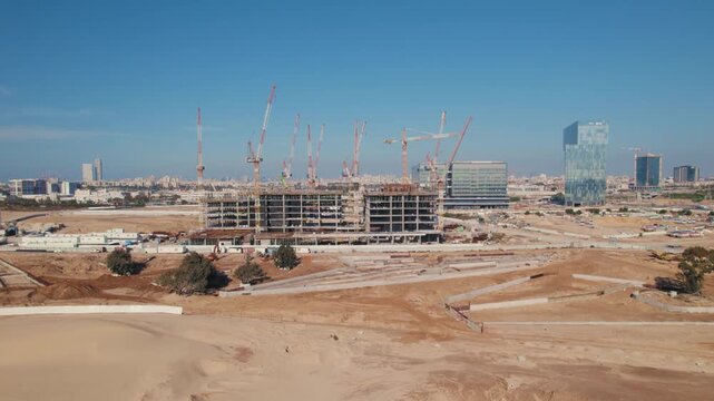 Aerial view of modern building construction site with multiple cranes working in industrial development zone.