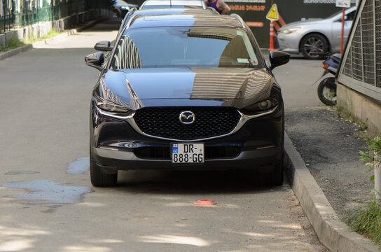 September 2, 2026, Tbilisi, Georgia Automotive street photography of a dark gray Mazda crossover SUV parked on a city street