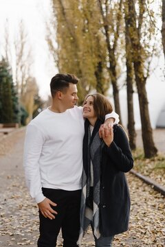 Couple walking along a tree-lined path, in a relaxed pose