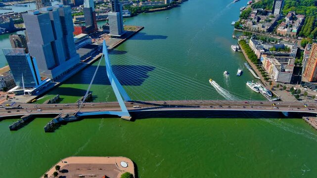 Aerial crane shot of the Erasmus Bridge pylon and cables over the Nieuwe Maas river with waterfront districts, Rotterdam, Netherlands