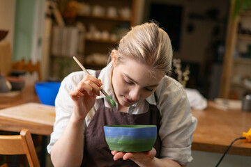 Making plate of clay in art studio. Young Woman making ceramic pottery.  Concept for workshop © murziknata