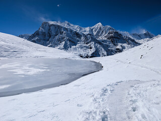 Fototapeta premium Frozen Ice Lake and Snow Covered Mountains in the Himalayas of Nepal