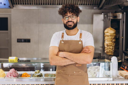 Young chef working in a shawarma restaurant kitchen, standing with crossed arms, preparing Middle Eastern street food