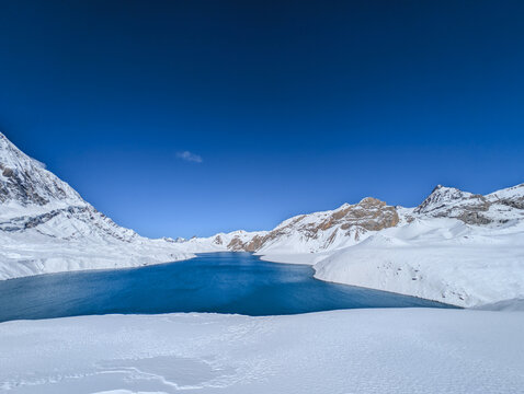 Deep blue high altitude Tilicho Lake surrounded by snow covered Himalayan mountains in Nepal