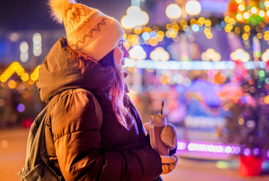 Girl With Cocoa At Christmas Market In Bright Lights In The Evening