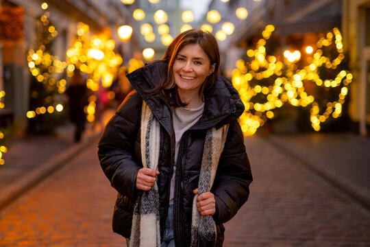 Happy Woman Standing On Christmas Street With Festive Lights In The Background