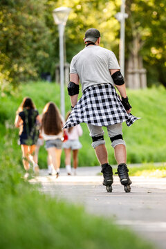 Person rollerblades on a paved outdoor trail while people walk in the background during daylight