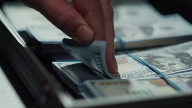 counting American hundred dollar banknotes putting money in metallic suitcase business