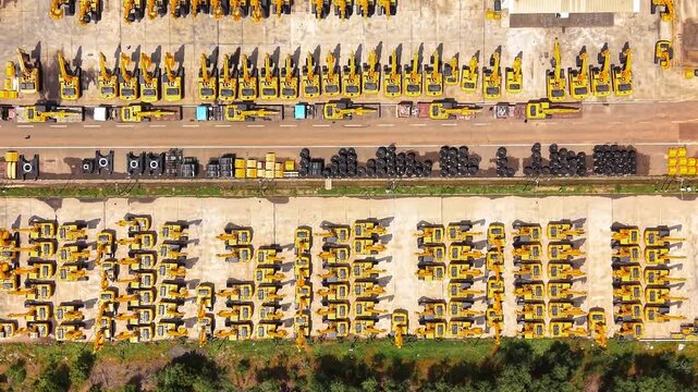 Rows of yellow construction cranes lined up at heavy equipment manufacturing yard industrial