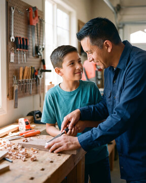 Attentive father teaching son woodworking at home garage workbench with warm natural light