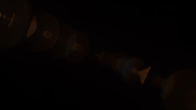 Golden Lens Flare radiating light with hexagonal bokeh during a dramatic cinematic transition over black