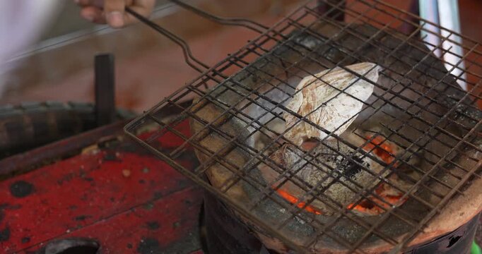 Thai vendor cooking ground dried squid on stove