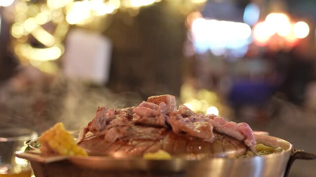 Preparation of roasted pork with sauce of vegetable on hot pot. Mu Kratha in night seen. Grilled sliced pork at Thai Barbecue style.