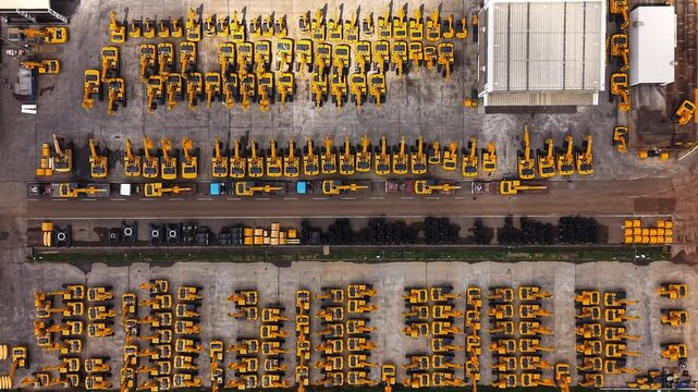 Yellow construction cranes and excavators arranged in rows at heavy equipment manufacturing yard industrial