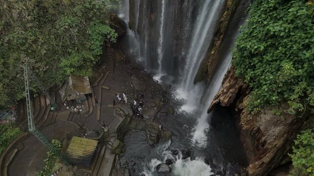 Majestic Waterfall Surrounded by Lush Greenery with Visitors Enjoying the Scenic View
