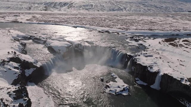 Aerial drone view of scenic godafoss waterfall in winter with snow covered landscape and flowing river in iceland.