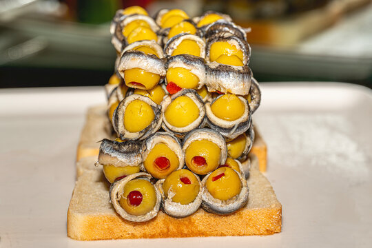 Traditional Turkish meze Hamsi Marin with olive, marinated white anchovy fillets in olive oil and herbs on a plate.