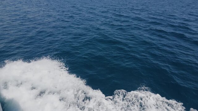 Close-up of white boat wake and sea foam churning across blue water, Cote d'Azur, France