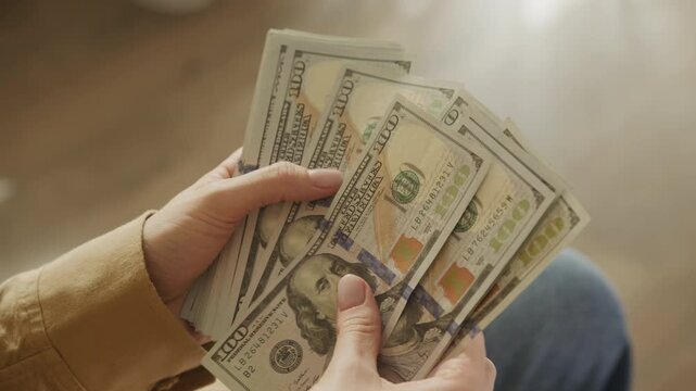 hands counting stack of one hundred dollar bills