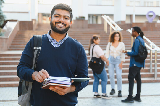 Indian male student smiling holding books on campus