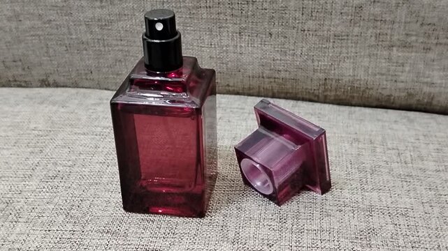 Elegant unbranded dark pink fragrance spray bottle displaying luxury cosmetics, personal care, and feminine beauty concepts, set against a soft beige woven textile surface.