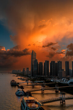 Dramatic sunset over the Wuhan skyline and Yangtze River. This fiery sky features "virga" phenomenon, where falling rain catches golden light, creating a stunning illusion of burning clouds.	
