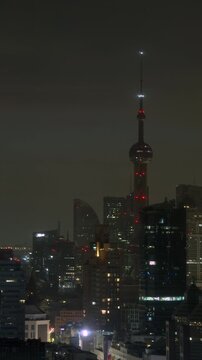 Night transitions into a golden sunrise over the Oriental Pearl Tower and Pudong skyline as morning daylight fills the sky in Shanghai, recorded in vertical timelapse