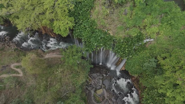 Breathtaking Aerial View of a Serene Waterfall Surrounded by Lush Greenery and Flowing River