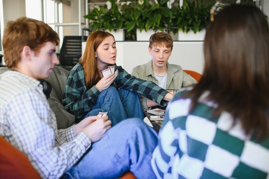 Group of teenagers playing board game cards at home