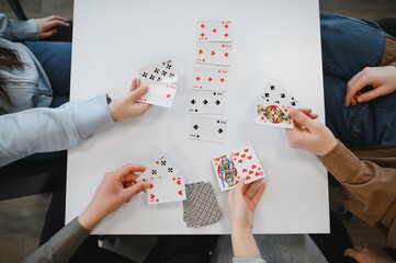 Obraz premium Friends playing cards at home, enjoying their free time
