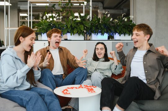 Excited young adults playing board game and celebrating victory