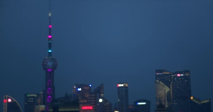 Thick fog clears over the Oriental Pearl Tower and Pudong skyscrapers as daylight turns to dark night with illuminated buildings in Shanghai, recorded in timelapse