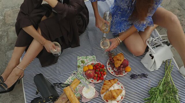 Overhead view of women pouring wine at a Paris picnic