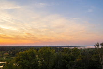 Fototapeta premium Colorful sunset over green valley with lakes and wetlands