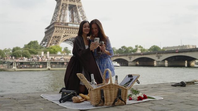 Women review smartphone photos with wine by the Eiffel Tower