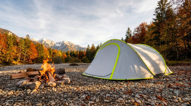 Tent with bonfire on rocky riverbank against autumn mountain forest, outdoor adventure and wilderness vacation