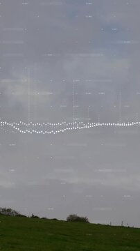 Wind turbine on grassy hill with sound wave animation over cloudy sky