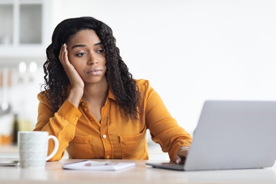 Worried Black Woman In Her 30s Working On Laptop At Home Office, Resting Her Head On Hand While Struggling To Focus On Task. Modern Workspace Creating Business Concept.