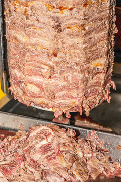  Close-up shot of a traditional Turkish d&ouml;ner kebab rotating on a vertical rotisserie spit at a street food market. [1] (https://www.shutterstock.com/search/d%C3%B6ner-kebap), [2] (https://www.shutter